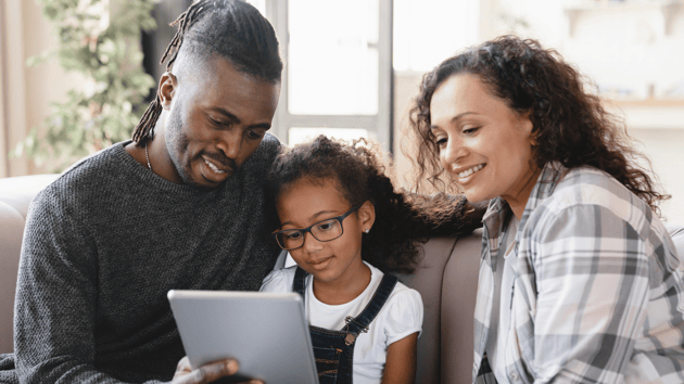 two parents and their daughter looking at a school on a tablet