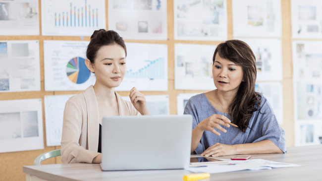 two women sitting at computer and talking about education