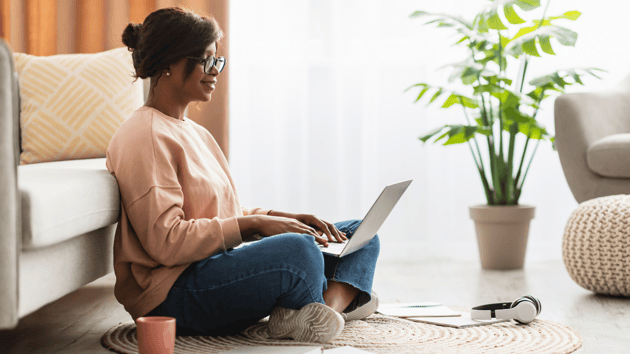 a happy mom sitting on the carpet with a computer to enroll her child
