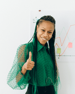 a teacher in a green shirt giving a happy thumbs up