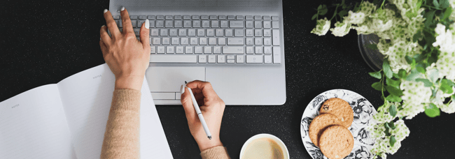 woman implementing a strategy at a computer with notebook