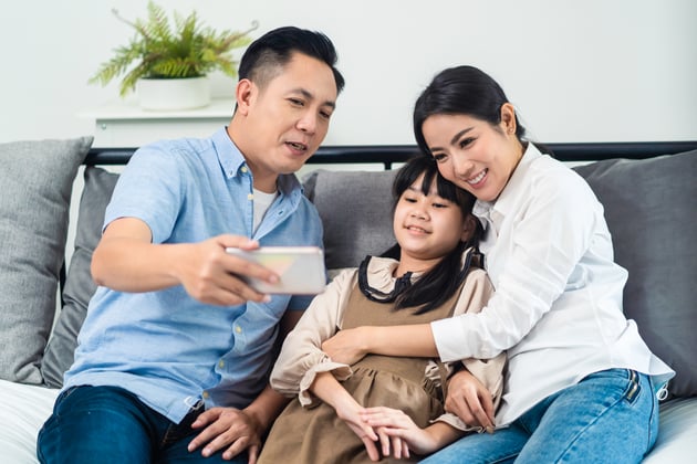 two parents and their child looking at a school website