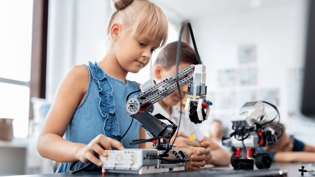 elementary girl working in school robotics lab with classmates