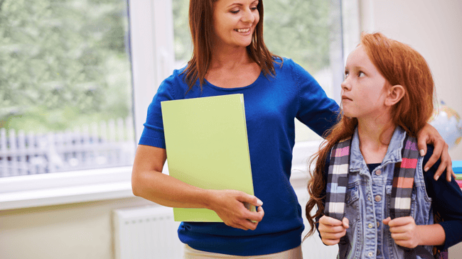female teacher walking and comforting young redhead girl