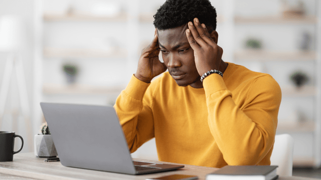 man in yellow shirt identifying burnout at computer