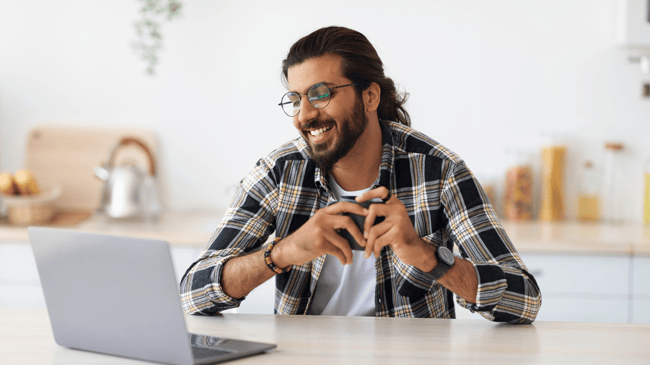 man sitting at desk looking at computer and smiling