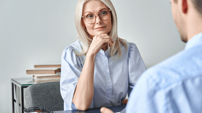 middle aged woman giving a teacher interview to a young man