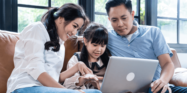 two parents and their child looking at a school website