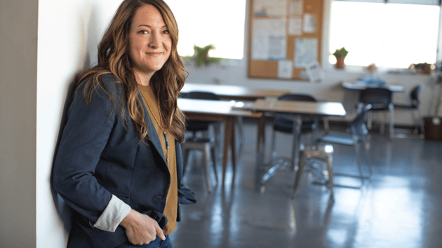 teacher leaning against door to classroom