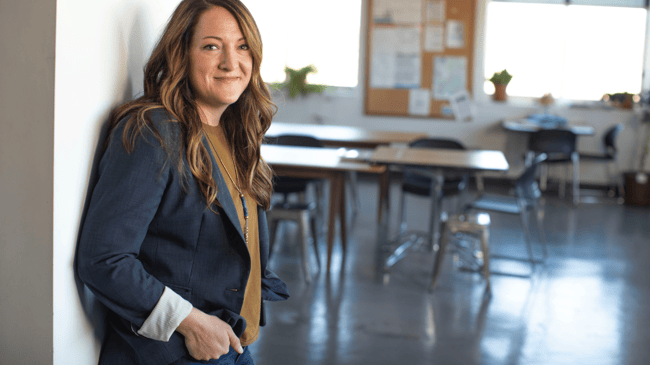 teacher leaning against door to classroom
