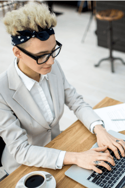 woman with tattoos typing on a computer