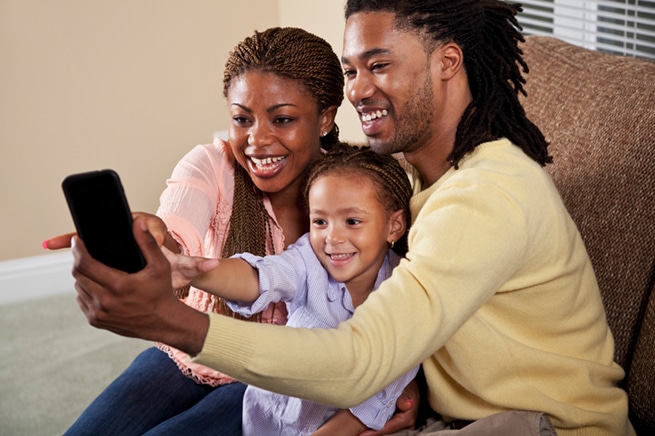 parents and child looking at a mobile phone for communication