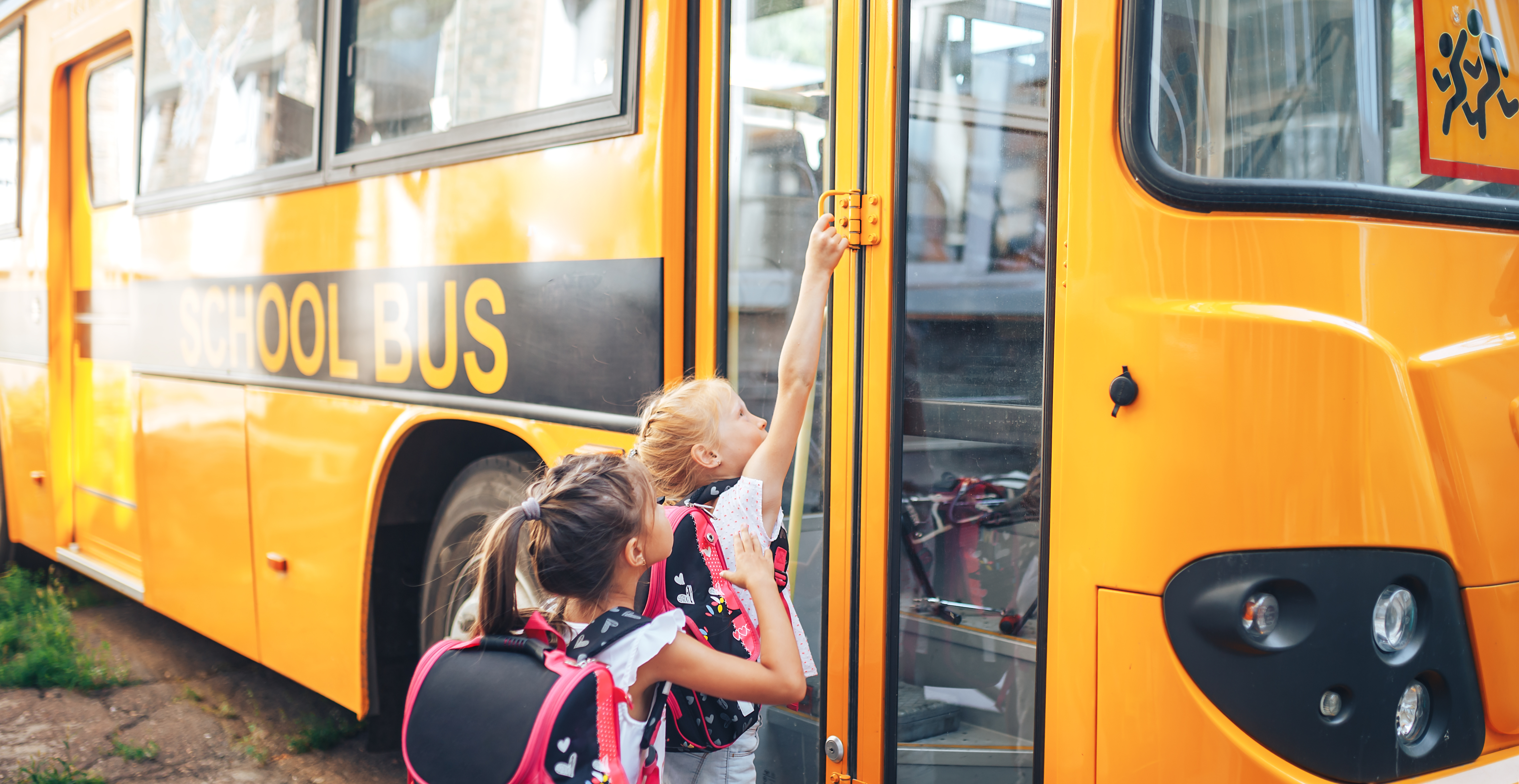 two young school girls getting on a bus